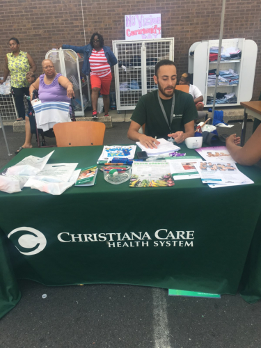 Man sitting on a chair waiting for the person to finish filling up the form and three ladies behind him.