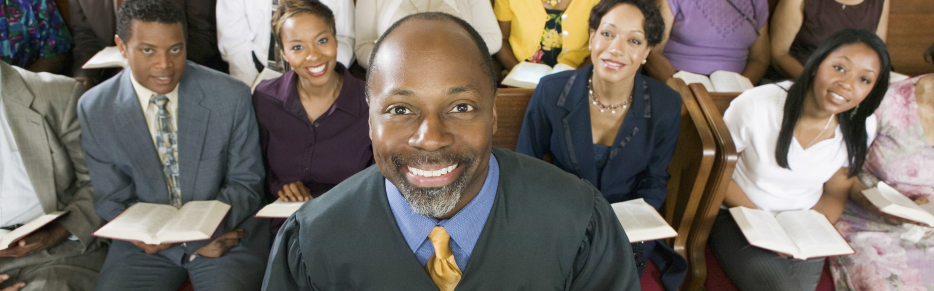 Portrait of confident preacher holding Bible with congregation sitting in church