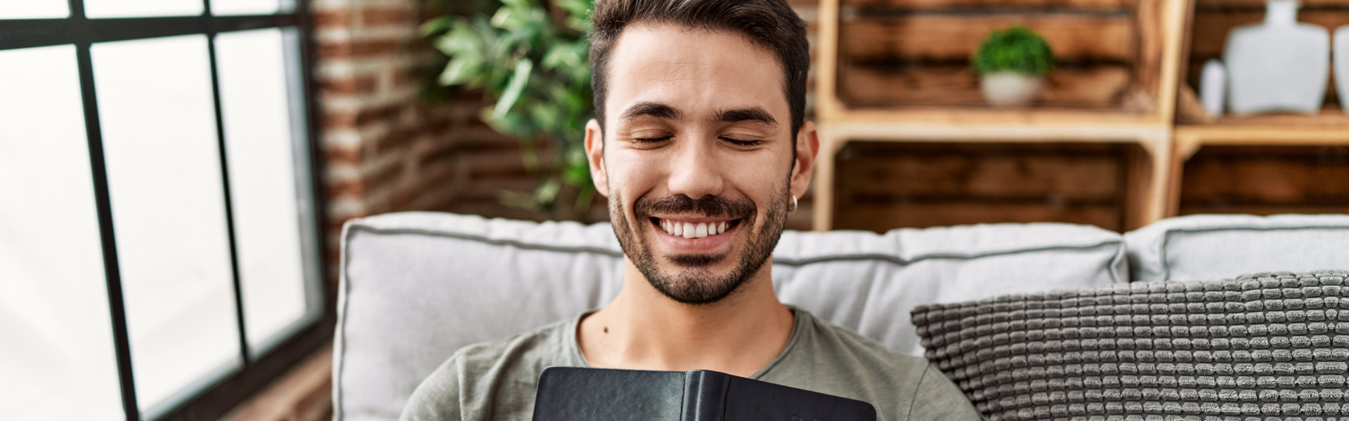 Young man smiling confident hugging bible at home